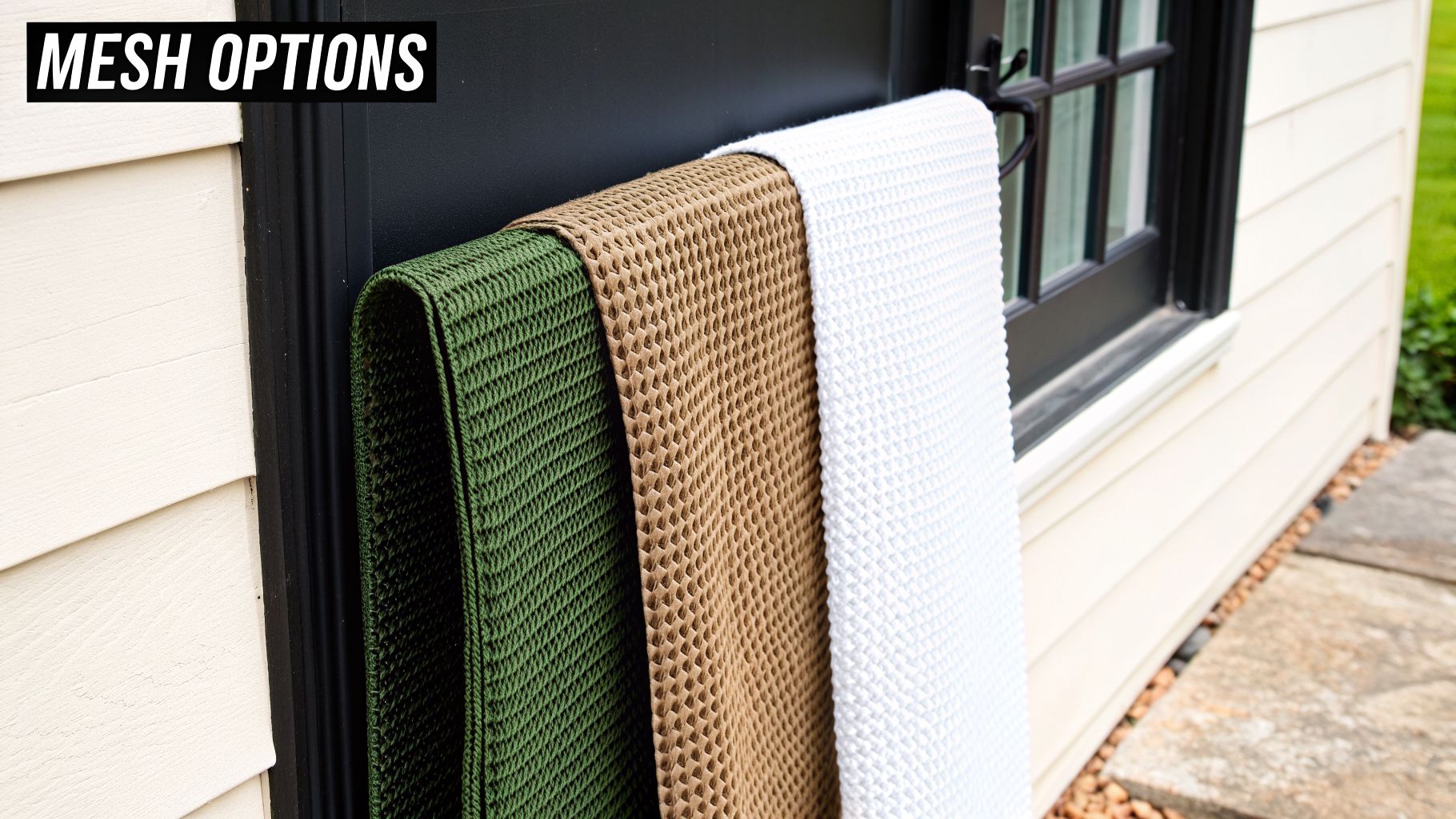 Three textured mesh fabric samples in green, brown, and white hanging on an outdoor rack.