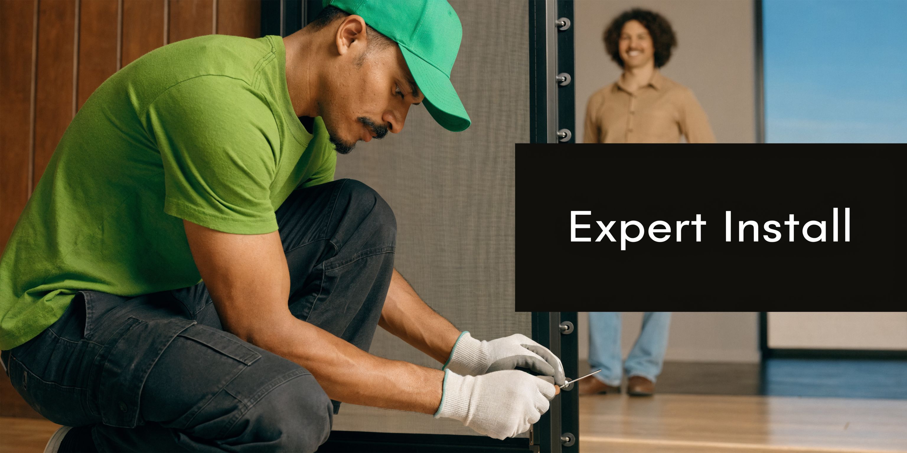 A professional installer in a green uniform and gloves installing a sliding screen door in a home.
