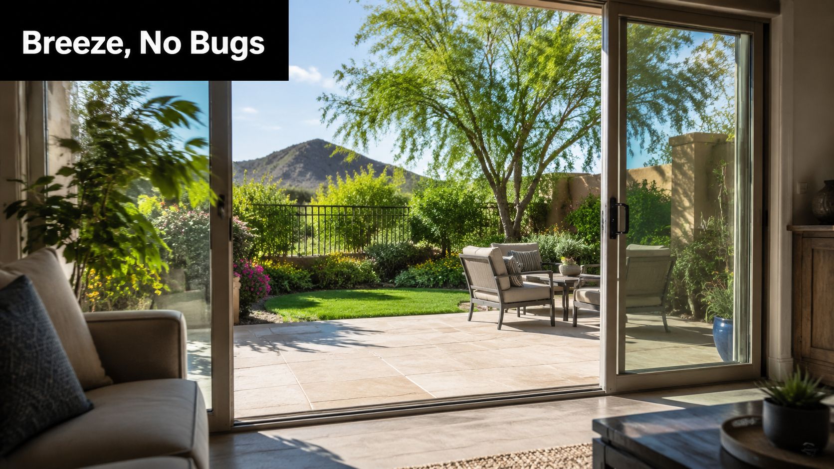 Open sliding glass door with a screen, revealing a beautiful sunny patio with outdoor seating and mountain views.