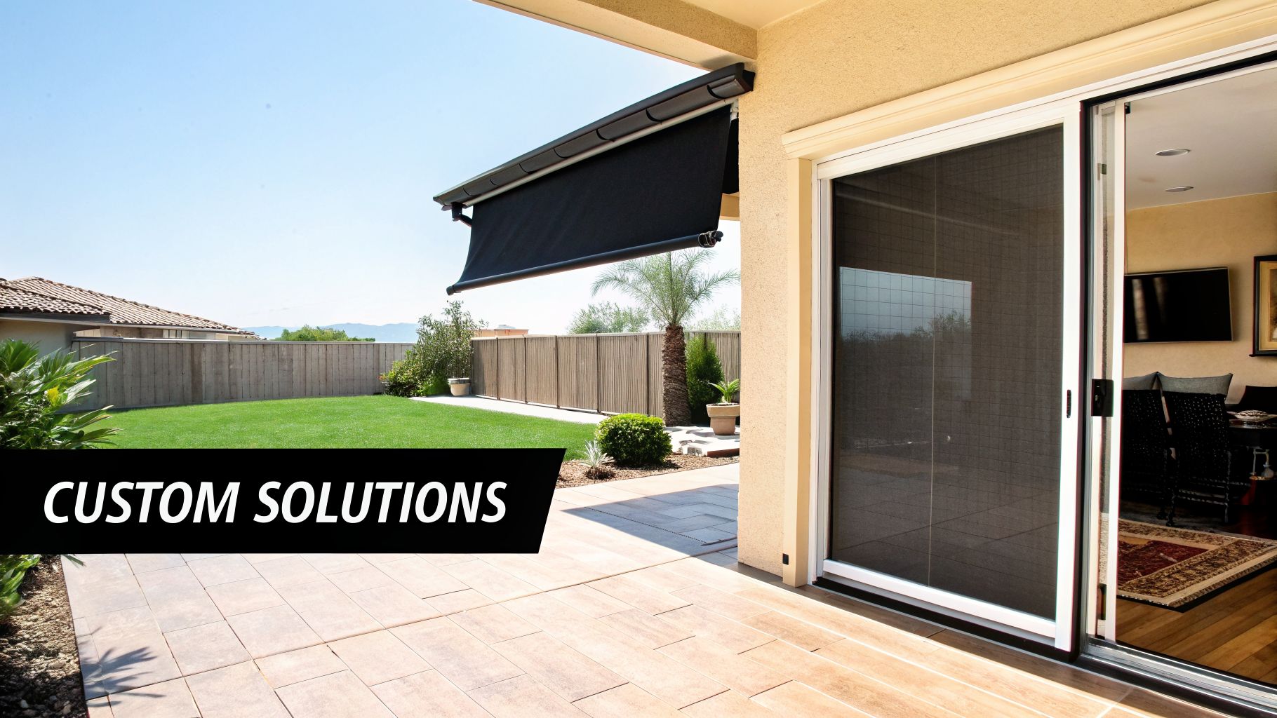 Modern patio with a black retractable awning, a sliding screen door, and lush green lawn.