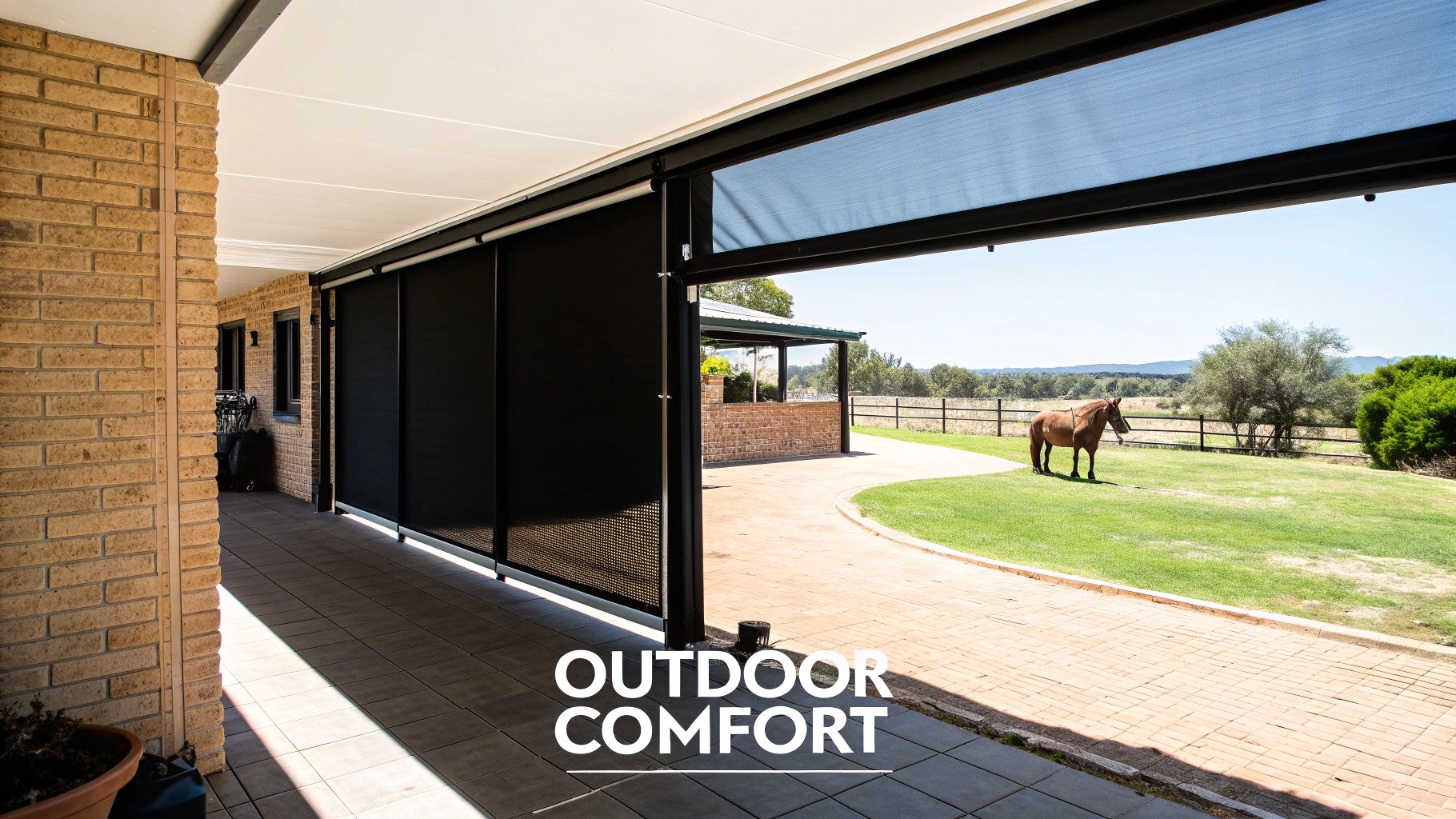Outdoor patio with retractable black sun screens, offering comfort and a view of a horse on a sunny field.
