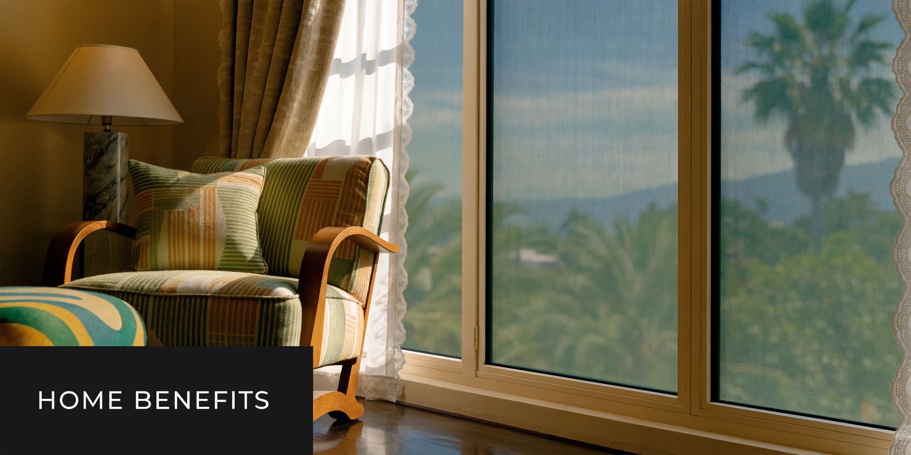 A comfortable armchair sits near a large window featuring tinted screens overlooking palm trees and mountains.