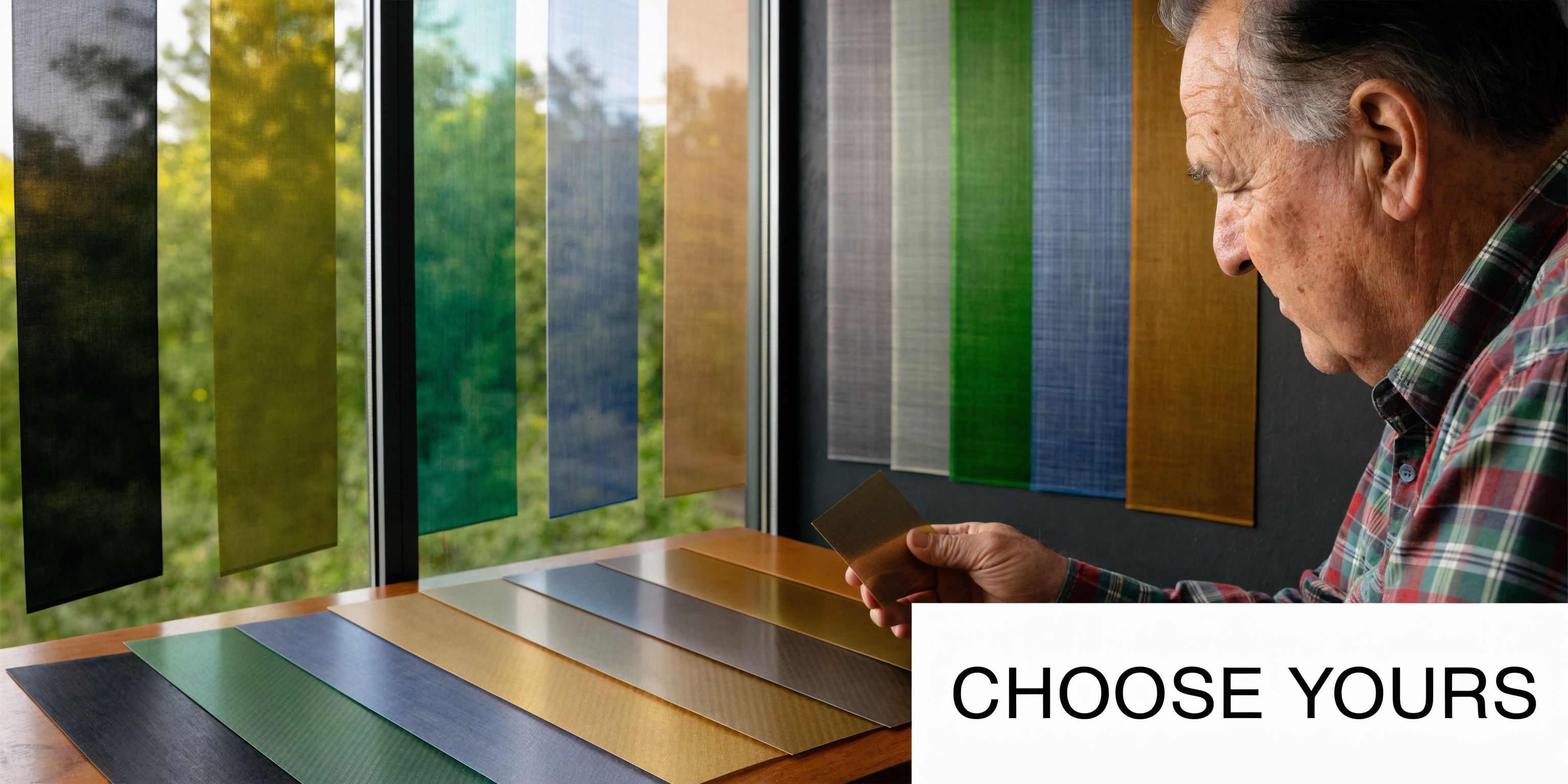 An elderly man examines various tinted screen samples for windows inside a modern home workspace setting.